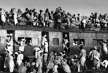 Mass migration during India's Partition in 1947 with people crossing trains and carrying belongings.