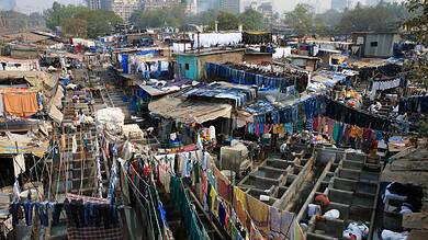 Overcrowded urban slum with hanging laundry and makeshift housing structures in a Mumbai.
