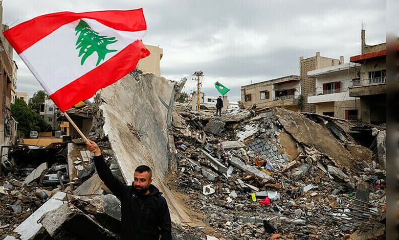 Man holding Lebanese flag in front of rubble and damaged buildings.
