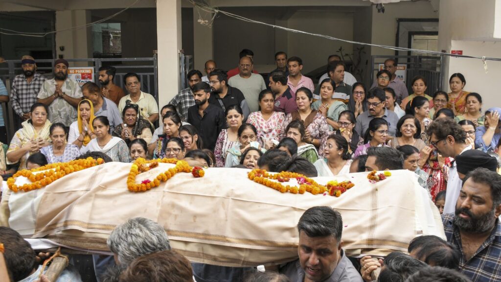 Large crowd gathered for a cultural or religious ceremony with a decorated coffin or shrine.