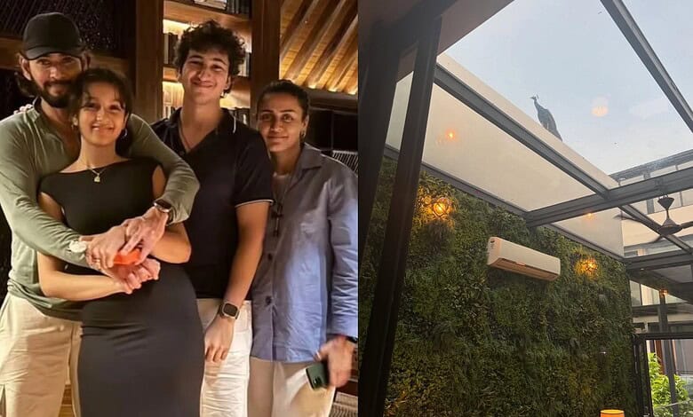 Group of four people smiling inside a modern glass house with greenery outside.