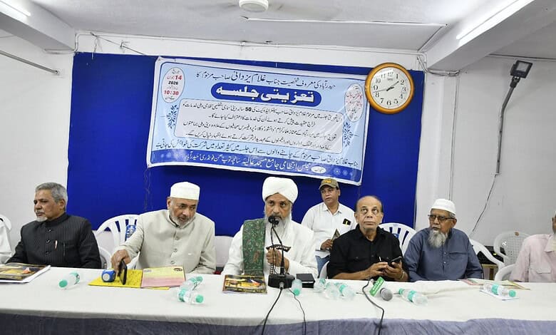 Group of men at a memorial event, some wearing traditional Islamic attire, seated at a table with a blue/.