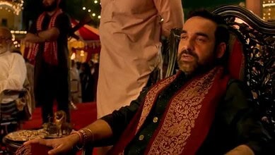 A man with a beard and traditional attire sitting on a decorated chair at a festive event.
