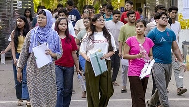 Students waiting in line for NEET retest after paper leak row, holding admit cards and documents.