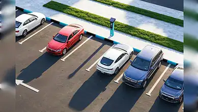 A public parking area with several cars parked in marked bays beside a payment machine in Sharjah.