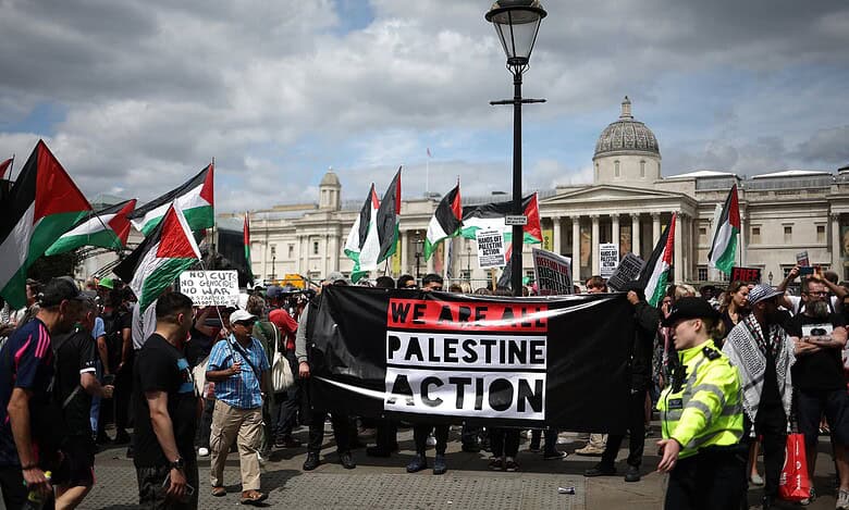 Protesters in London holding a Palestine Action banner during a demonstration for Palestinian rights.