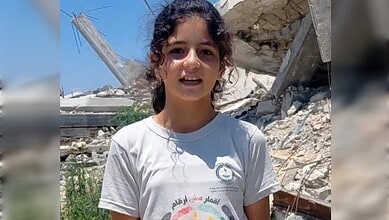 Palestinian 13-year-old Eileen al-Farra stands before the rubble of damaged buildings in southern Gaza.