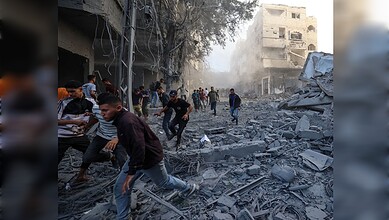People amidst rubble and destruction in an urban area after a disaster.