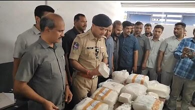 Police officer inspecting seized adulterated paneer with group of men in background.