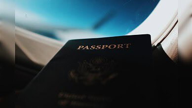 Passport resting on a car dashboard with a view of the night sky through the windshield.