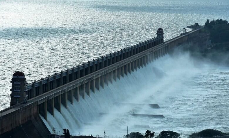 Dam releasing water into the river with mist and trees in the background.