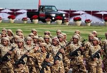 Soldiers in uniform participating in a military parade, standing in formation with rifles, during a forma.