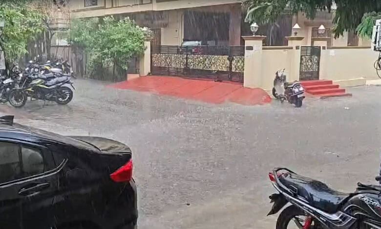 Flooded street with parked motorcycles and cars during heavy rain in an urban area.