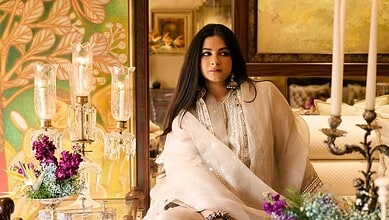 Rhea Kapoor wearing elegant traditional attire with floral decor in the background.