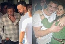 A man and woman hugging and smiling at a social event, surrounded by other people.