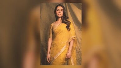 Elegant woman in a yellow saree posing against a neutral background.