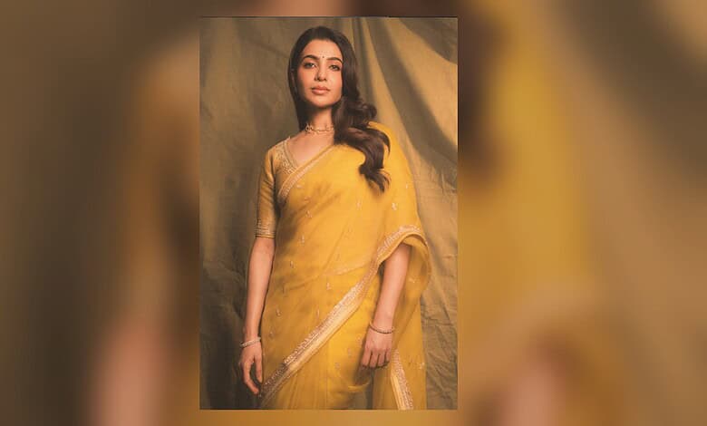 Elegant woman in a yellow saree posing against a neutral background.