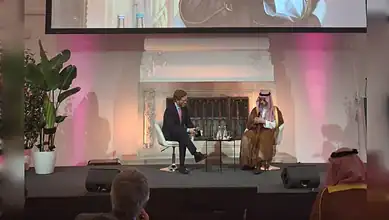 Saudi business leader in traditional attire being interviewed on stage at a conference.