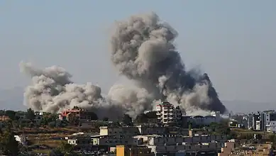 Large smoke clouds rise from buildings in Lebanon after Israeli strikes, despite ceasefire efforts.