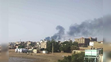 Urban skyline with smoke rising from distant buildings in Hyderabad, India.