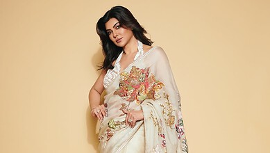A woman in a traditional embroidered saree posing against a plain background.