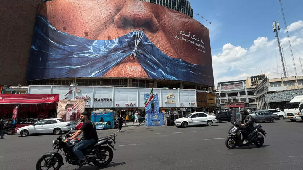 A billboard in central Tehran depicts a stylised image of sewn lips over the Strait of Hormuz, while vehicles and pedestrians move through the square on May 2, 2026.