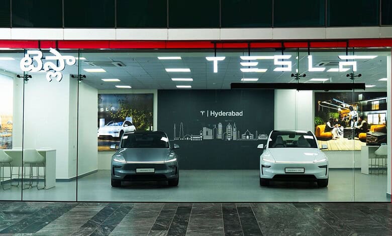 Tesla showroom displaying two electric cars inside with a modern interior and branding.