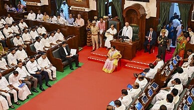 Governor delivering speech to assembly members in legislative chamber during session.