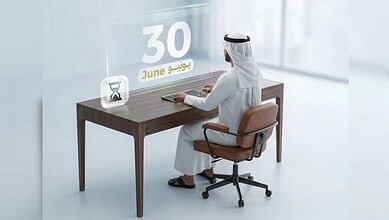 Businessman in traditional attire working at desk with June 30 calendar and hourglass.