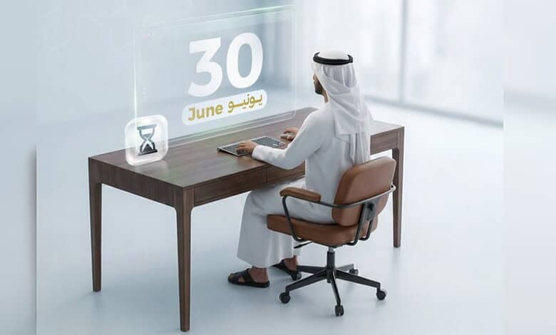 Businessman in traditional attire working at desk with June 30 calendar and hourglass.