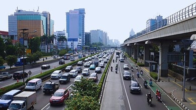 Busy city street with heavy traffic and high-rise buildings in the background.