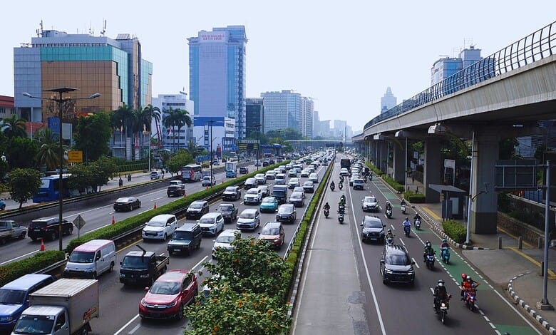 Busy city street with heavy traffic and high-rise buildings in the background.