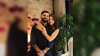 Virat Kohli and Anushka Sharma smiling and embracing each other indoors.