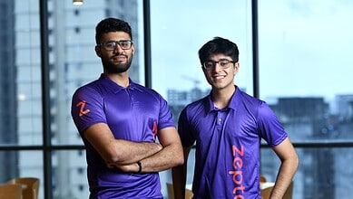 Team members in matching blue sports shirts smiling at the camera in an office setting.