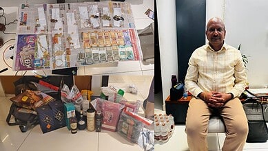 Display of seized cash, gold, and goods in an investigation scene with a man sitting nearby.