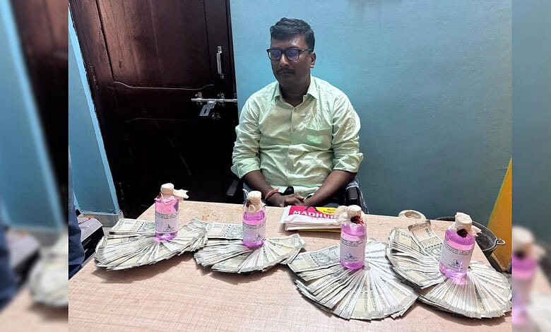Man sitting at a table with stacks of money and water bottles in front of him.