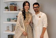 A woman and a man in traditional Indian attire posing indoors.