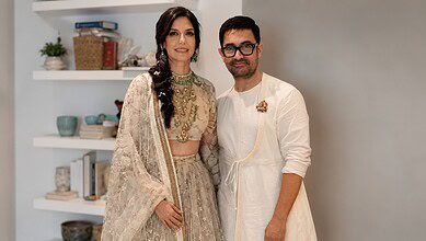 A woman and a man in traditional Indian attire posing indoors.