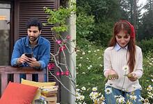 Young man and woman enjoying outdoor time, woman holding daisies, man using smartphone.