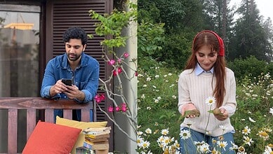 Young man and woman enjoying outdoor time, woman holding daisies, man using smartphone.
