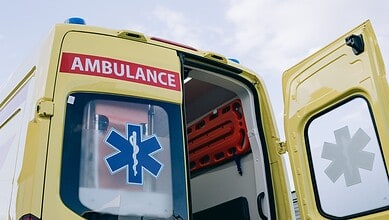 Yellow ambulance with open door and medical symbols, ready for patient transfer.