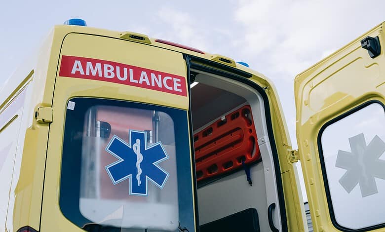 Yellow ambulance with open door and medical symbols, ready for patient transfer.