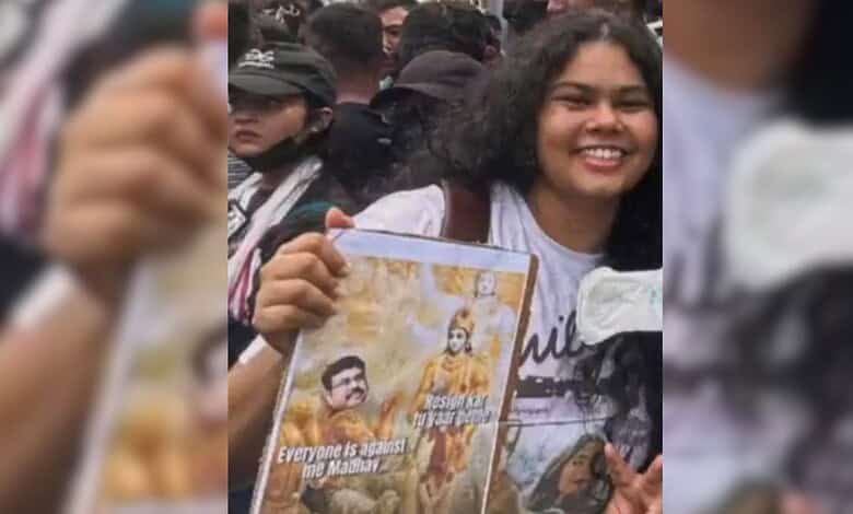 Daughter of Assam minister joins protest, holding a poster with political slogans.