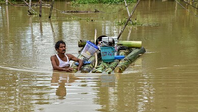 Man on makeshift raft in floodwaters with belongings during a flood rescue.