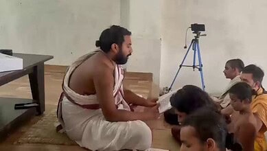 Man in traditional attire reading to children during a ritual at Ayodhya Ram temple.