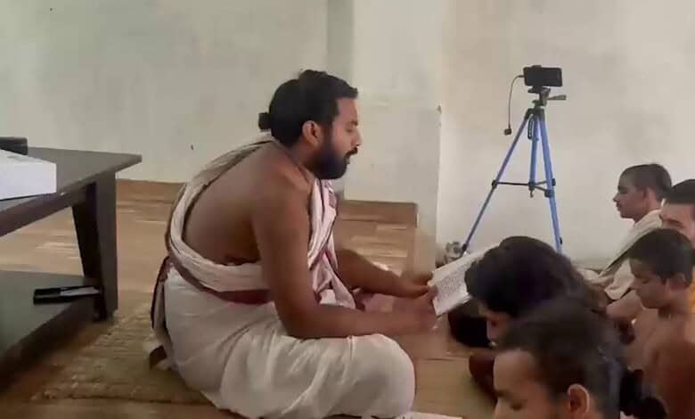 Man in traditional attire reading to children during a ritual at Ayodhya Ram temple.