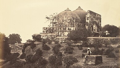 Historic black and white photo of Babri Masjid with a person sitting nearby.