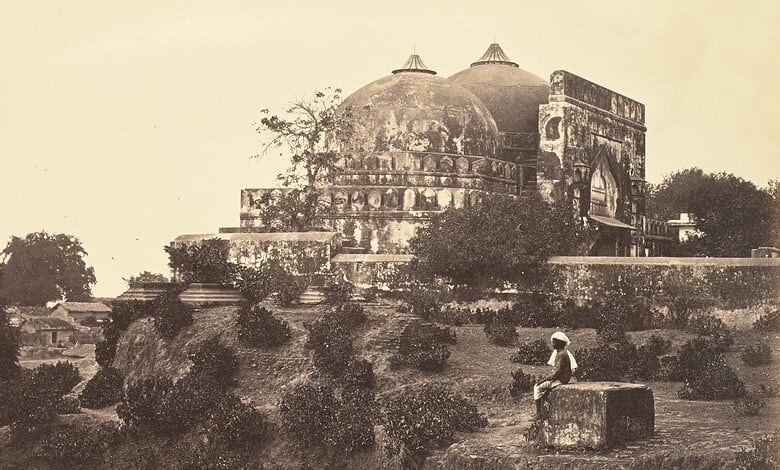 Historic black and white photo of Babri Masjid with a person sitting nearby.