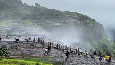 Tourists enjoy the mist and scenic views at the reverse waterfall in Maharashtra during a trip from Hyder.
