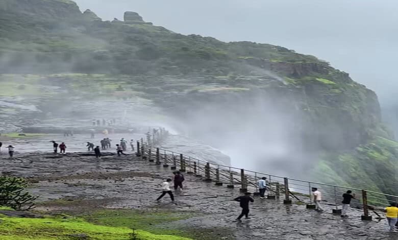 Tourists enjoy the mist and scenic views at the reverse waterfall in Maharashtra during a trip from Hyder.